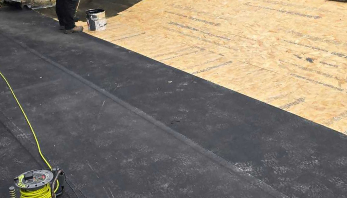 EPDM rubber membrane being rolled out and bonded over a new timber deck