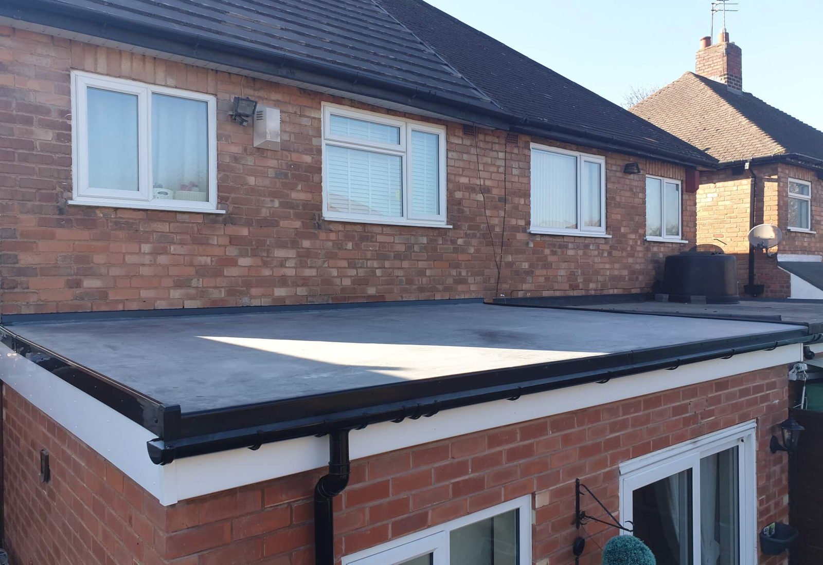 Newly completed dark flat roof with matching guttering on a brick home near Sutton Coldfield