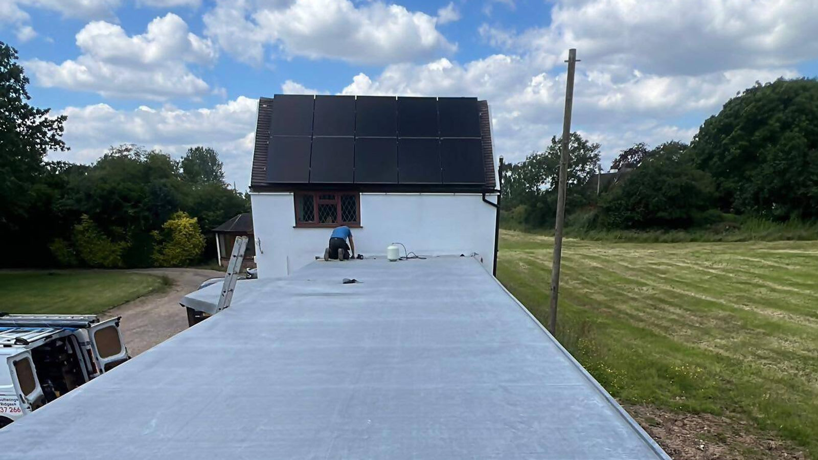 Newly installed flat roof on a large building with a roofer finishing the surface, Birmingham