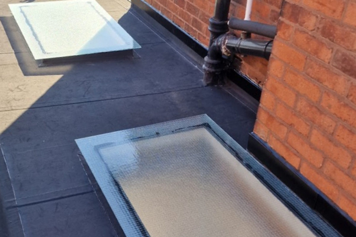 After: the same roof re-covered in dark EPDM with two new glazed rooflights